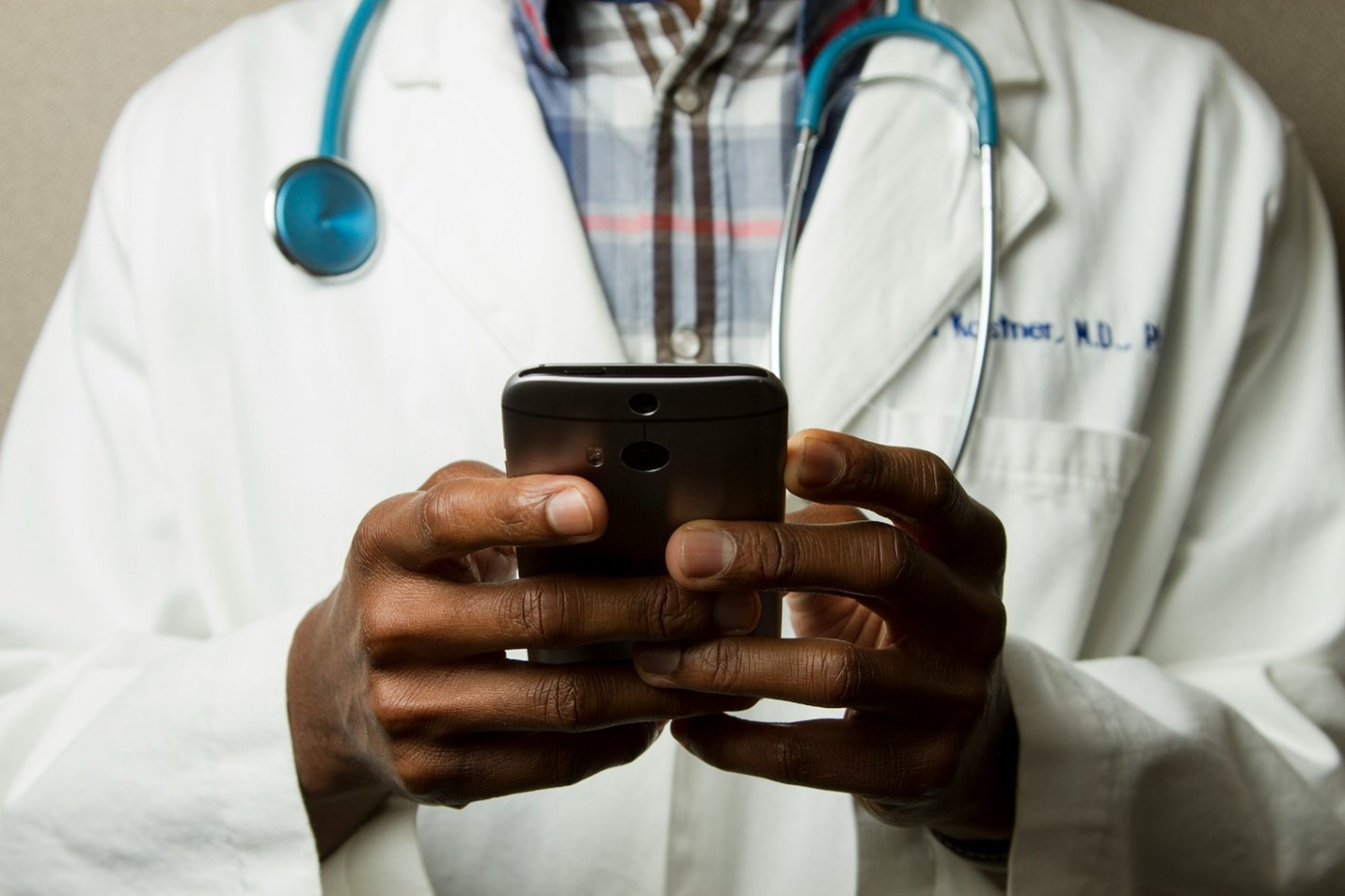 Arzt hält Smartphone, Symbolbild fuer CYbersicherheit im Gesundheitswesen