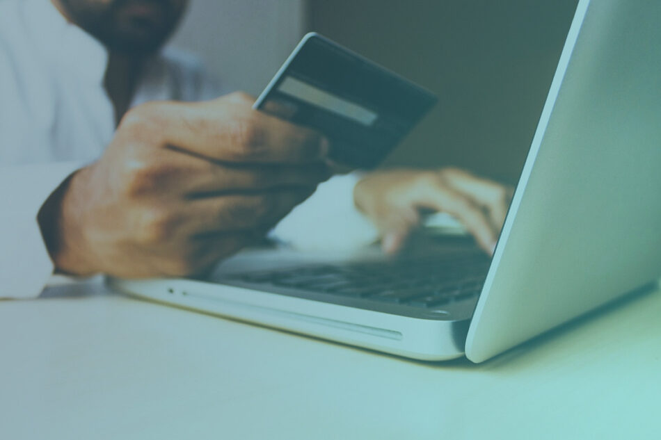 Image of someone typing on a laptop while holding a credit card